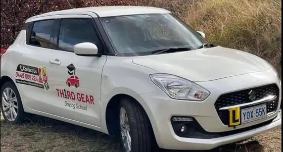 The lesson car: a white automatic Suzuki Swift with Third Gear Driving School signs and an L plate